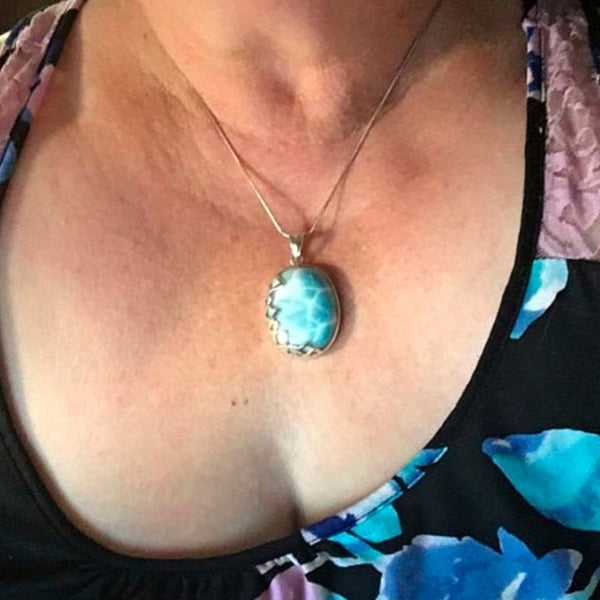 Close-up of a Larimar necklace with a blue Larimar pendant worn by a person.
