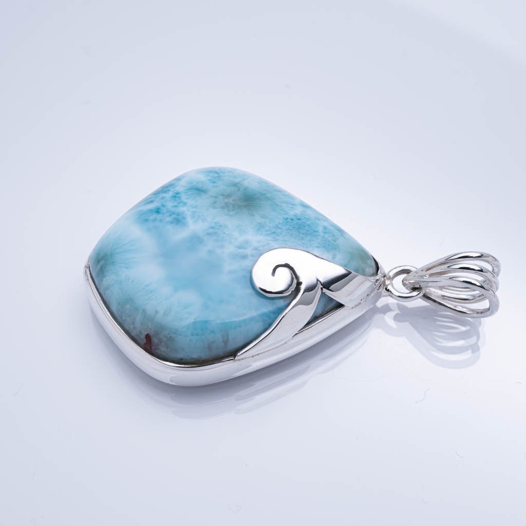 Larimar pendant with silver wave design on a light gray background