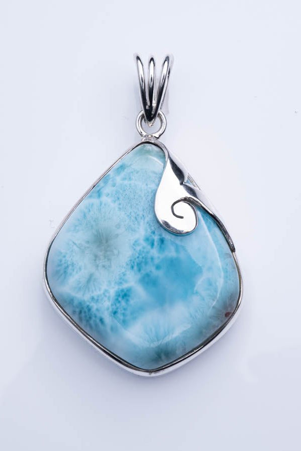 Blue stone pendant with silver setting on a light gray background