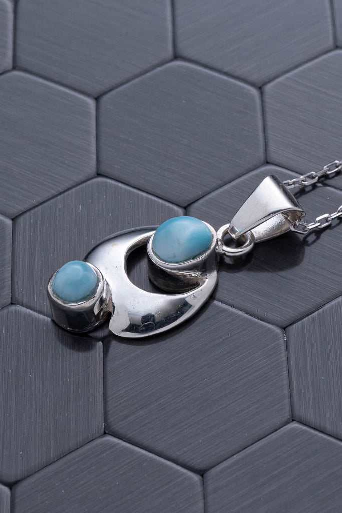 Silver necklace with turquoise stones on a hexagonal patterned surface