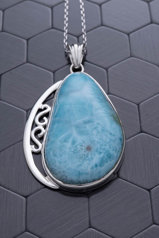 Turquoise pendant necklace on a dark hexagonal patterned background