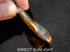 Close-up of a polished Dominican blue amber cabochon glowing under light.