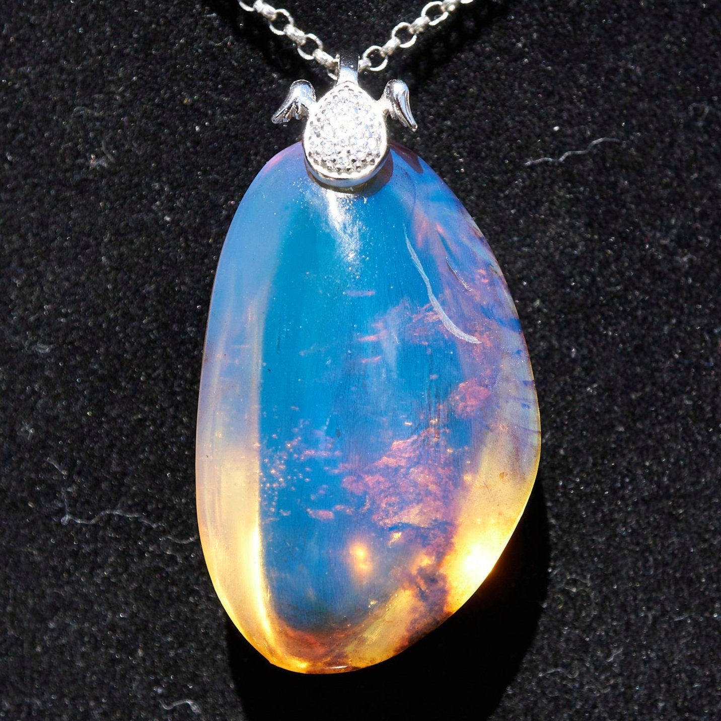 Handcrafted Dominican amber pendant with glowing blue and golden highlights, featuring unique gemstone details and artisan craftsmanship