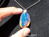 Handcrafted Dominican amber pendant with glowing blue and golden highlights, featuring unique gemstone details and artisan craftsmanship