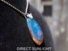 Handcrafted Dominican amber pendant with glowing blue and golden highlights, featuring unique gemstone details and artisan craftsmanship