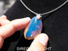 Handcrafted Dominican amber pendant with glowing blue and golden highlights, featuring unique gemstone details and artisan craftsmanship