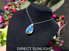 Handcrafted Dominican amber pendant with glowing blue and golden highlights, featuring unique gemstone details and artisan craftsmanship