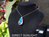 Handcrafted Dominican amber pendant with glowing blue and golden highlights, featuring unique gemstone details and artisan craftsmanship