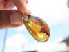 Handcrafted Dominican amber pendant with glowing blue and golden highlights, featuring unique gemstone details and artisan craftsmanship