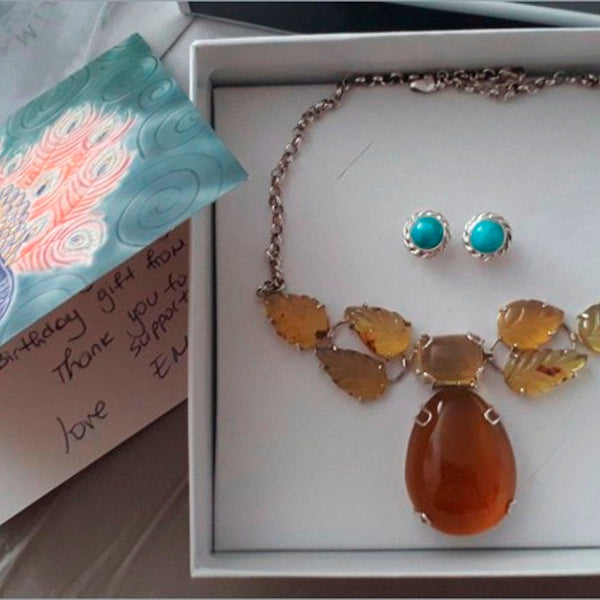 Jewelry set with a necklace and earrings in a box, accompanied by a card.