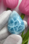 Close-up of a polished natural Larimar cabochon in a smooth teardrop shape, showcasing vibrant oceanic blue hues with subtle white marbling, perfect for jewelry making or as a collectible gemstone