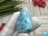 Close-up of a polished natural Larimar cabochon in a smooth teardrop shape, showcasing vibrant oceanic blue hues with subtle white marbling, perfect for jewelry making or as a collectible gemstone