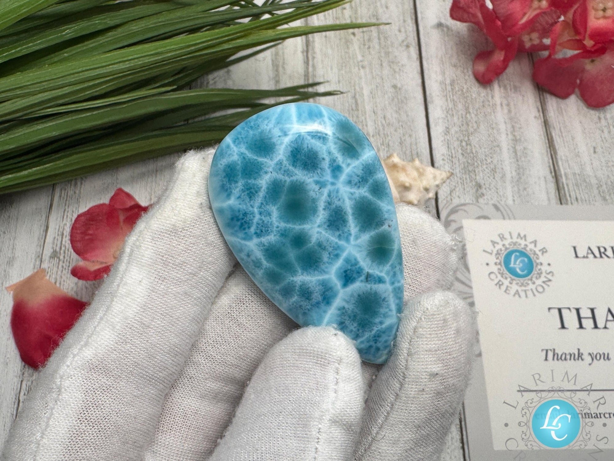 Close-up of a high-quality Larimar cabochon with vibrant Caribbean blue hues and natural white patterns, polished