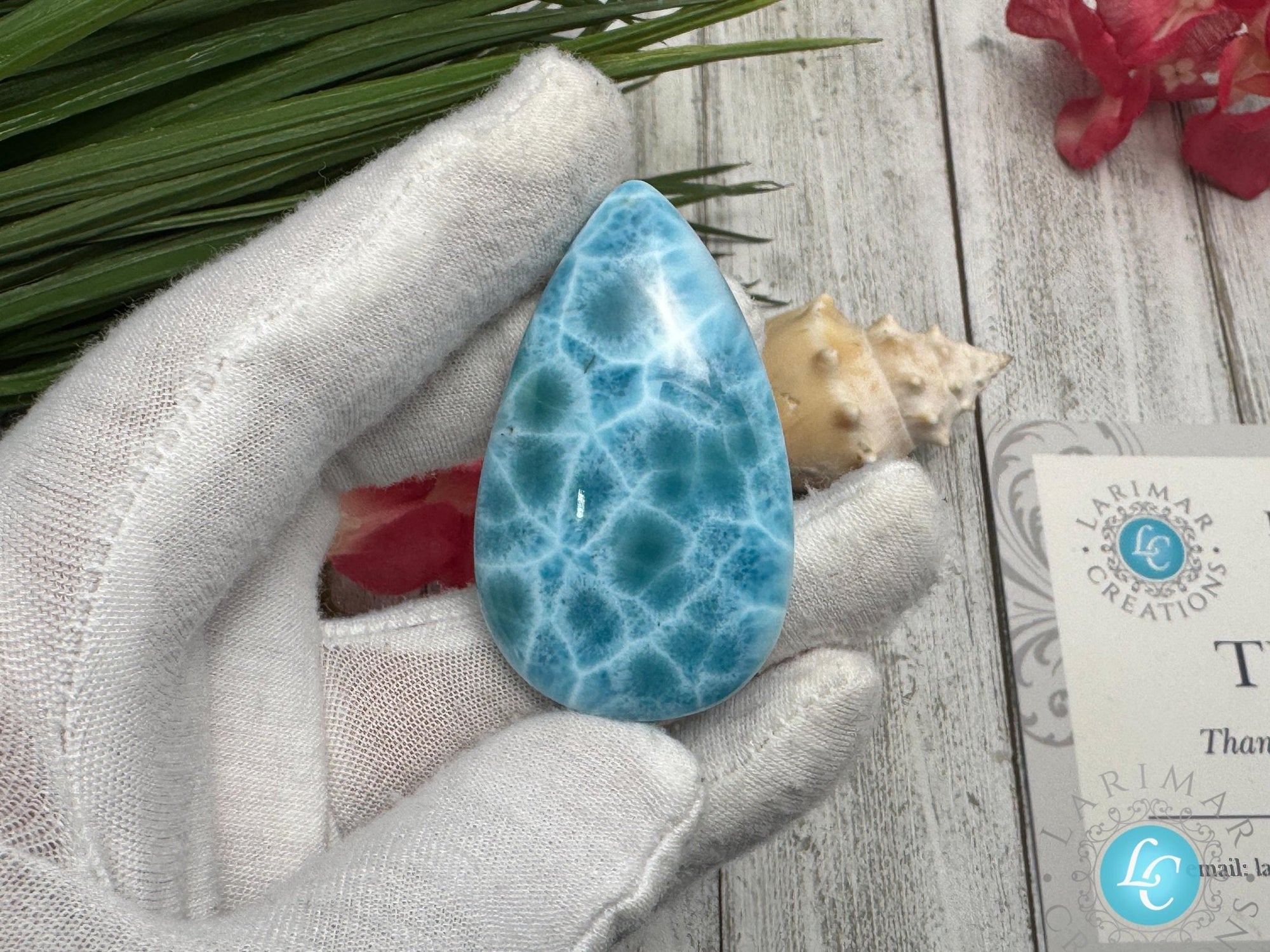 Close-up of a high-quality Larimar cabochon with vibrant Caribbean blue hues and natural white patterns, polished