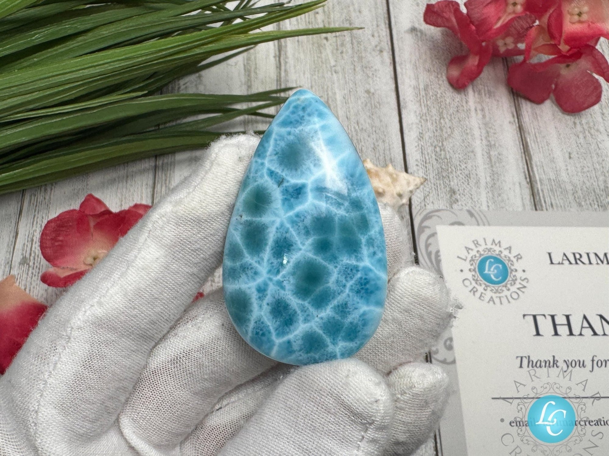 Close-up of a high-quality Larimar cabochon with vibrant Caribbean blue hues and natural white patterns, polished