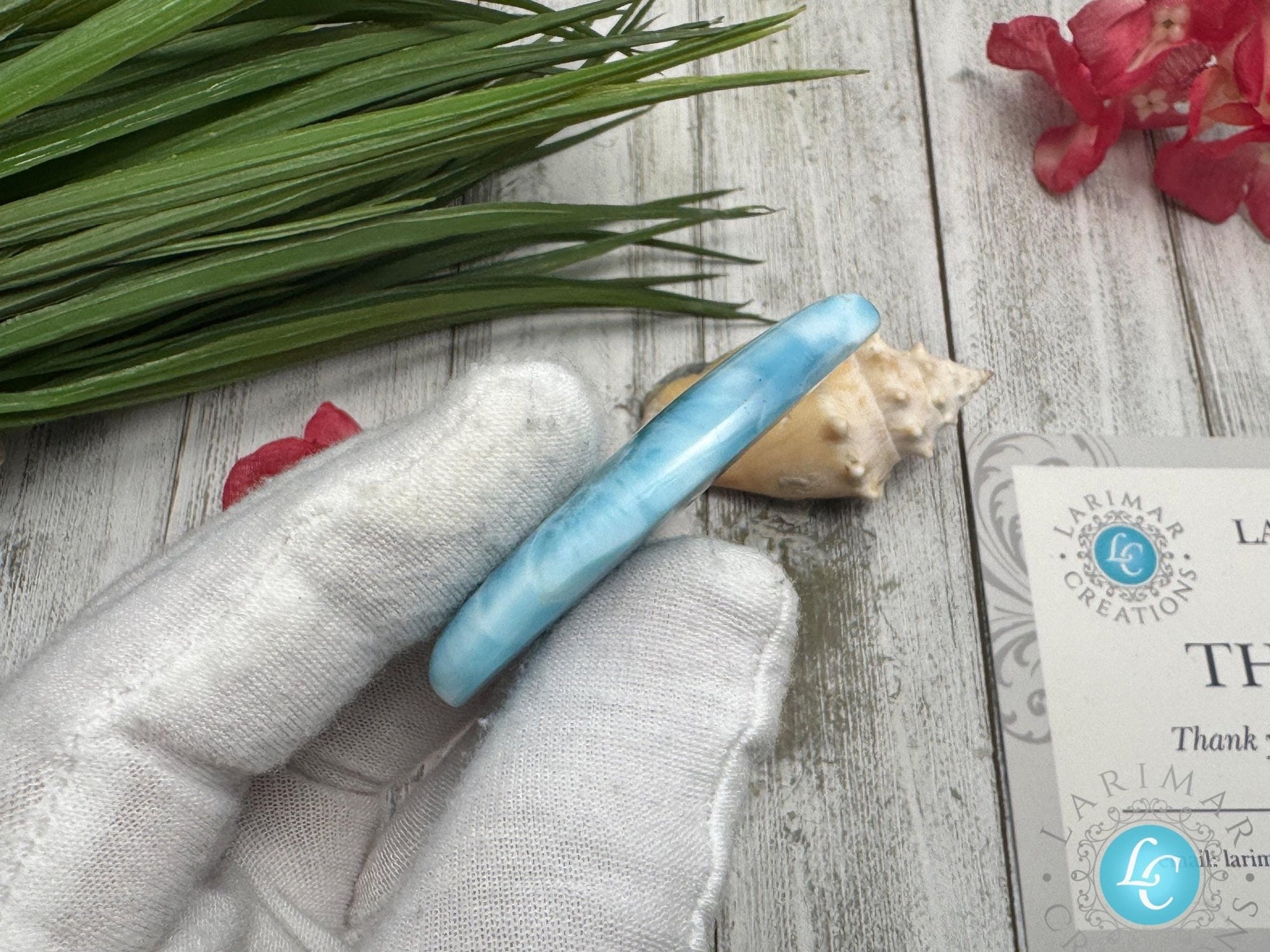 Close-up of a high-quality Larimar cabochon with vibrant Caribbean blue hues and natural white patterns, polished