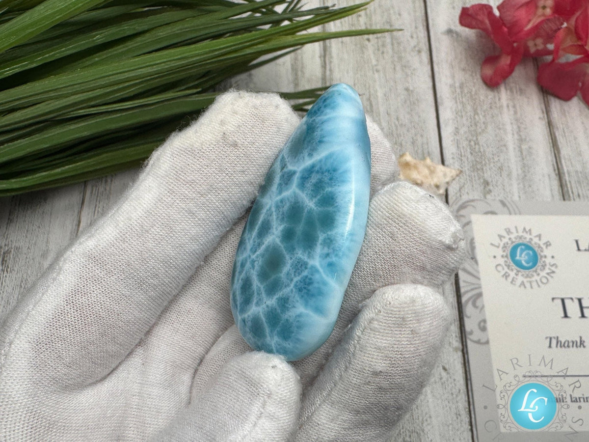 Close-up of a high-quality Larimar cabochon with vibrant Caribbean blue hues and natural white patterns, polished