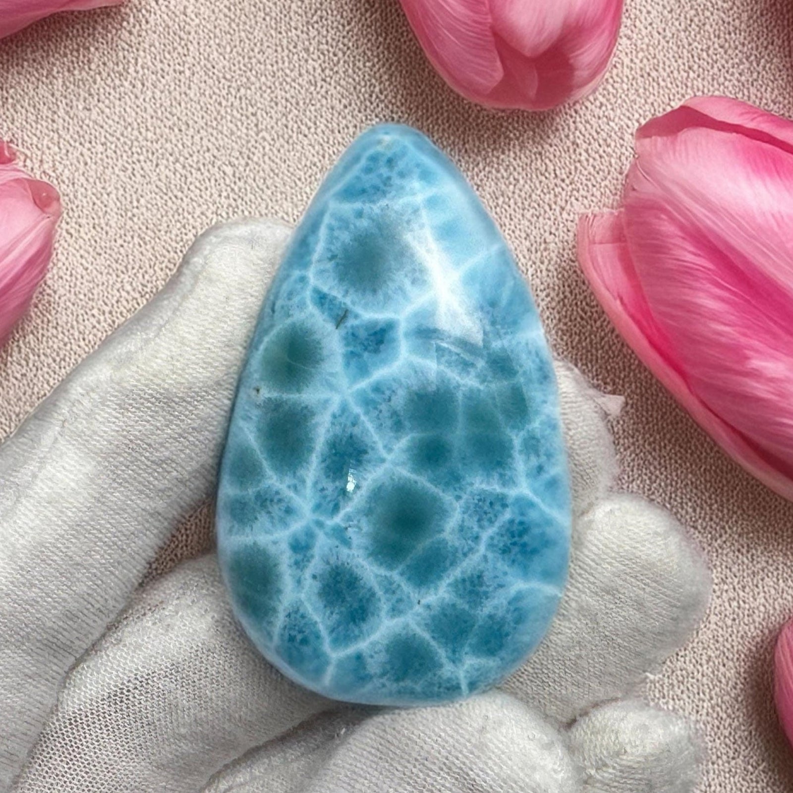 Close-up of a high-quality Larimar cabochon with vibrant Caribbean blue hues and natural white patterns, polished