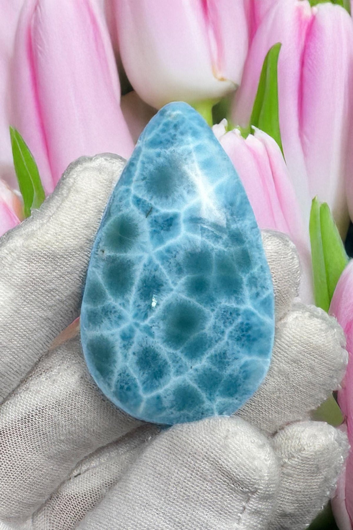 Close-up of a high-quality Larimar cabochon with vibrant Caribbean blue hues and natural white patterns, polished