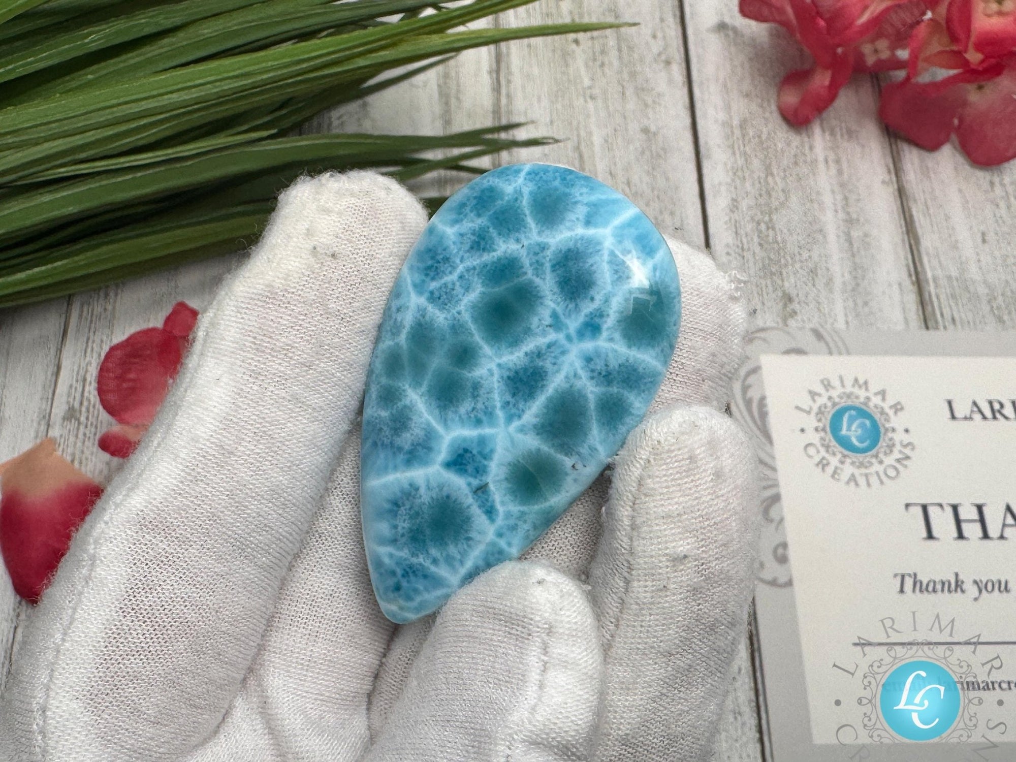 Close-up of a high-quality Larimar cabochon with vibrant Caribbean blue hues and natural white patterns, polished