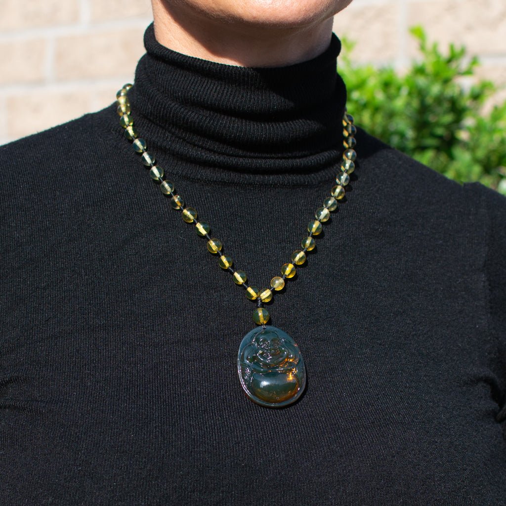 Person wearing a black turtleneck with a beaded necklace featuring a pendant.