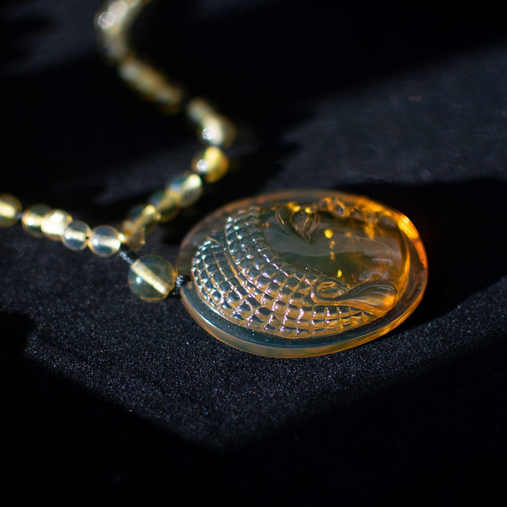 Person wearing a black turtleneck with a Amber necklace featuring a large pendant.