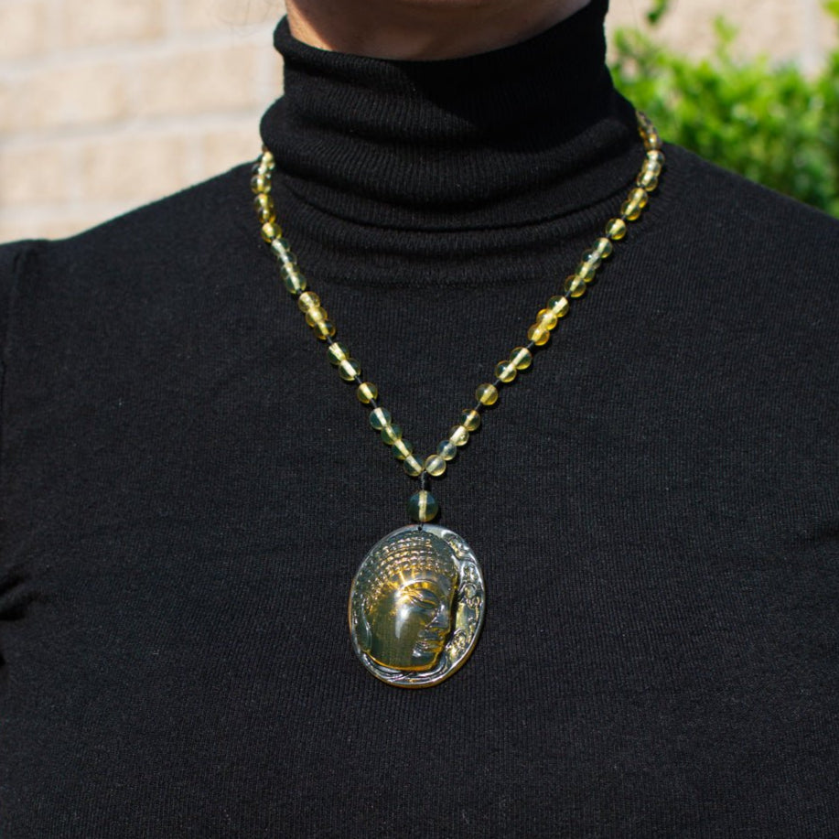 Person wearing a black turtleneck with a Amber necklace featuring a large pendant.