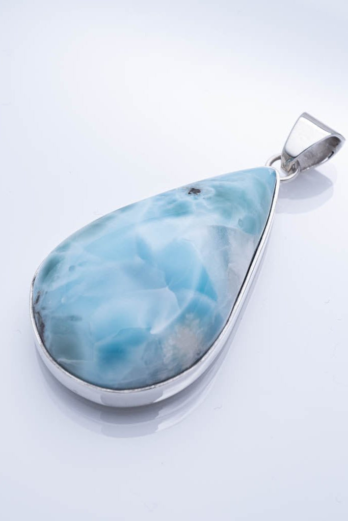 Teardrop-shaped larimar pendant on a light gray background