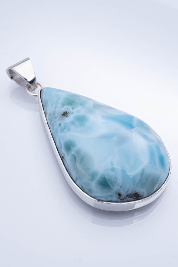 Teardrop-shaped larimar pendant on a white background