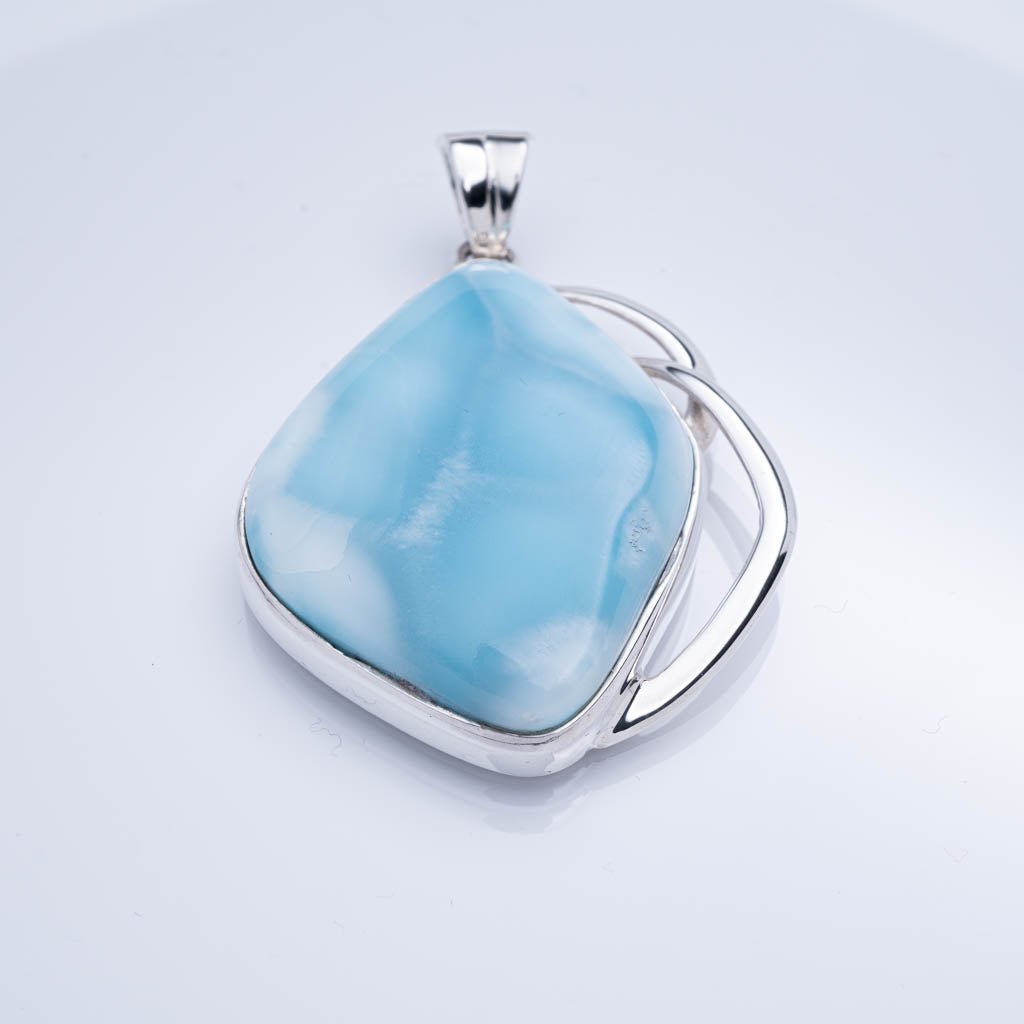 Blue larimar pendant with silver setting on a light gray background