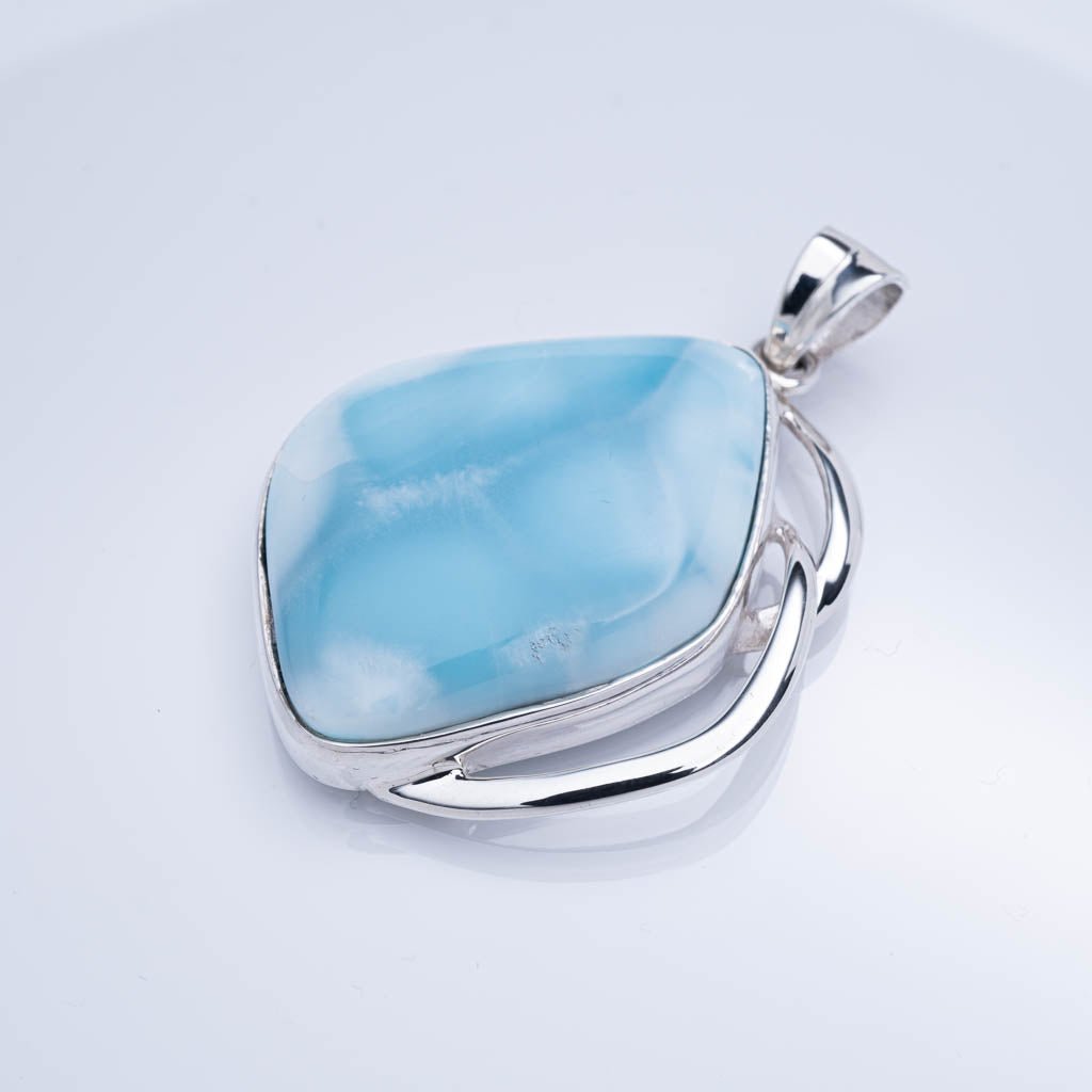 Blue larimar stone pendant with silver setting on a light gray background