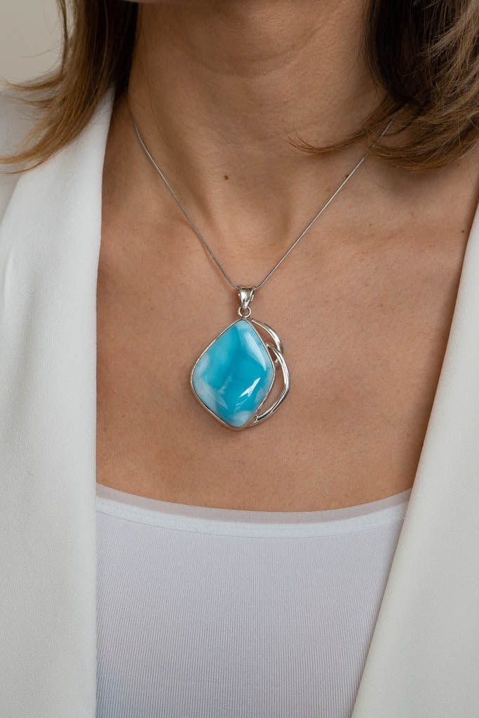 Turquoise pendant necklace worn by a person in a white outfit
