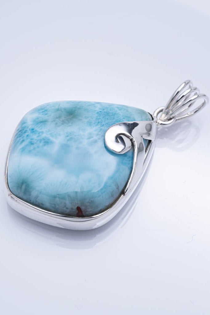 Blue larimar pendant with silver setting on a light gray background