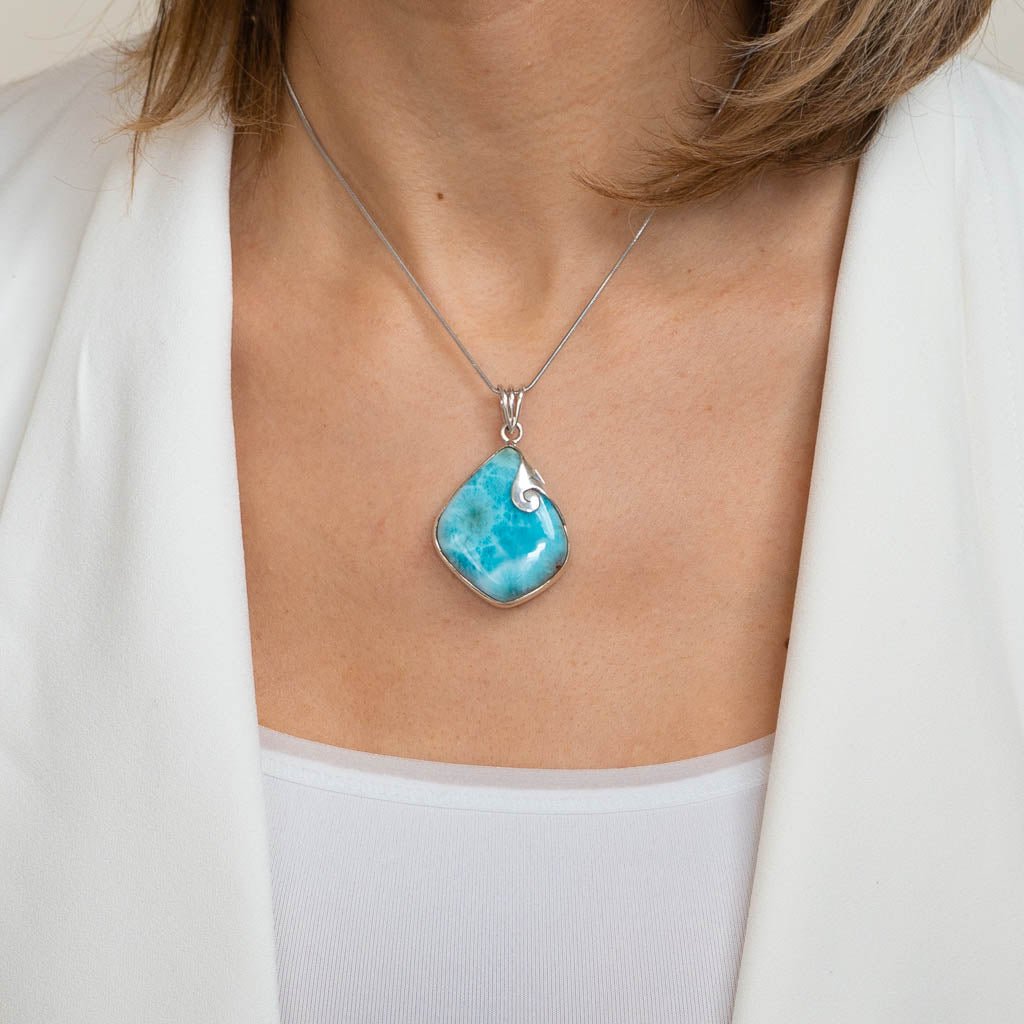 Turquoise pendant necklace on a person wearing a white outfit