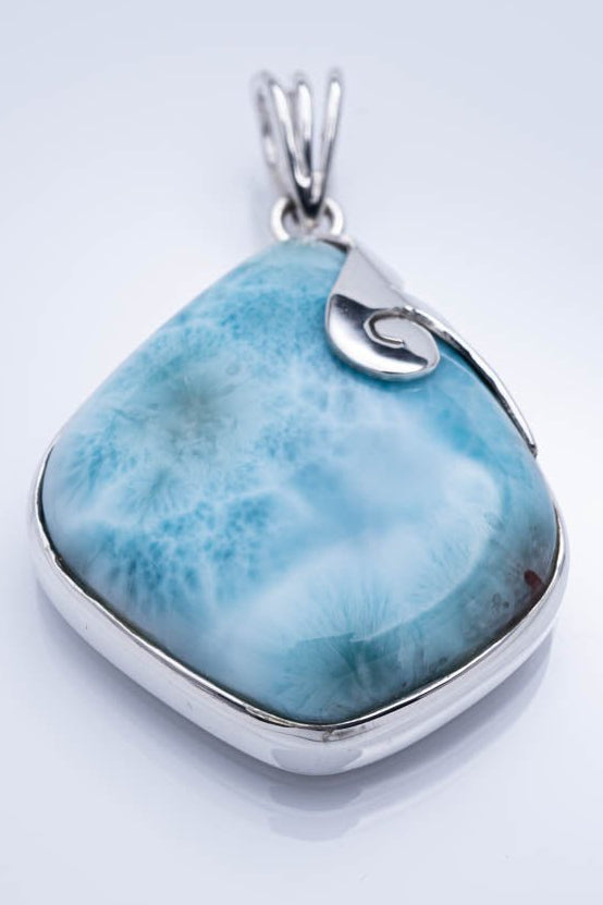 Turquoise stone pendant with silver setting on a light gray background