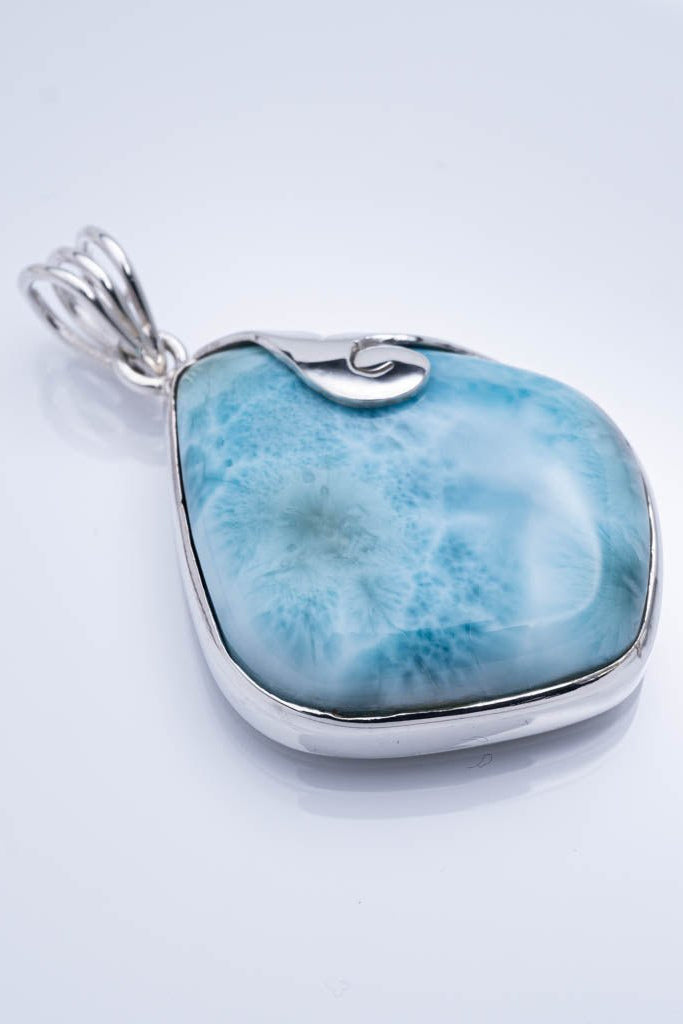 Blue larimar pendant with silver setting on a light gray background