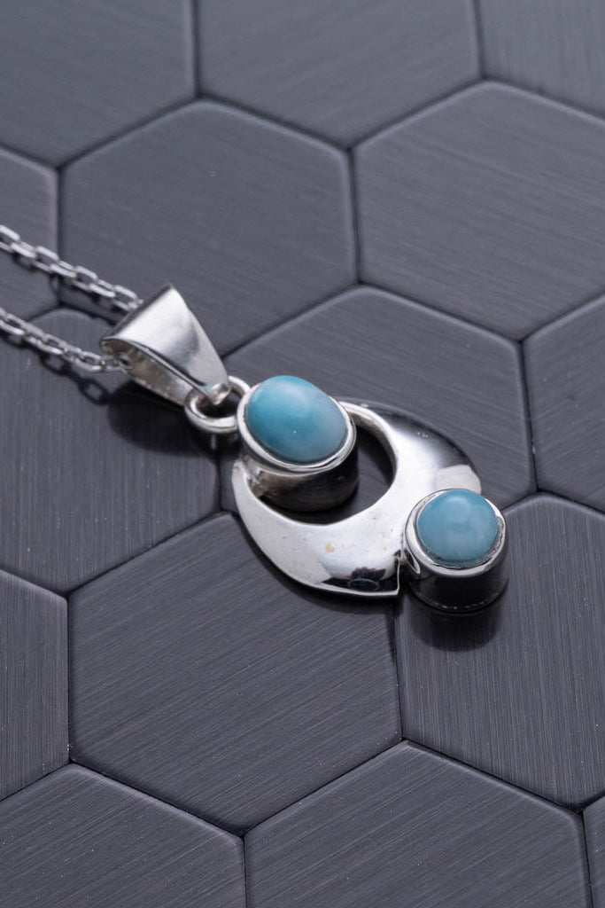 Silver necklace with turquoise stones on a hexagonal patterned surface