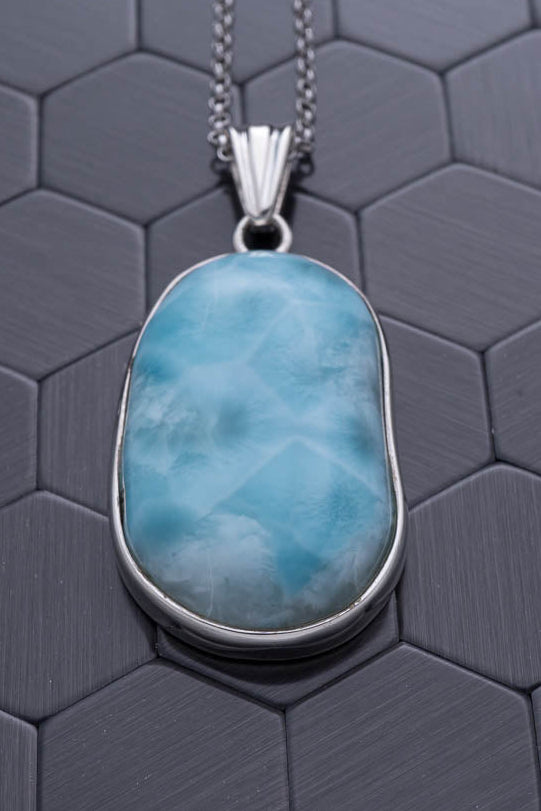 Blue pendant necklace on a hexagonal patterned surface