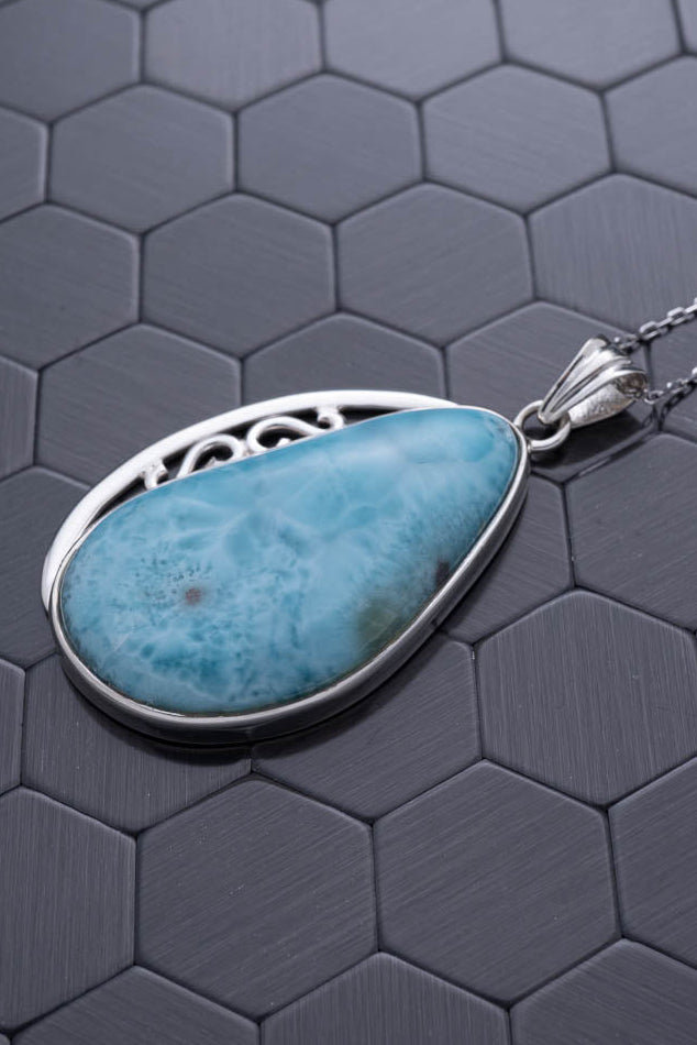 Turquoise pendant necklace on a hexagonal patterned surface